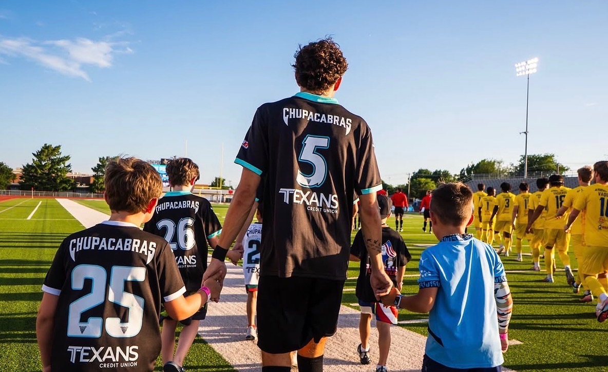 Evan Lupo walking onto the field with young players